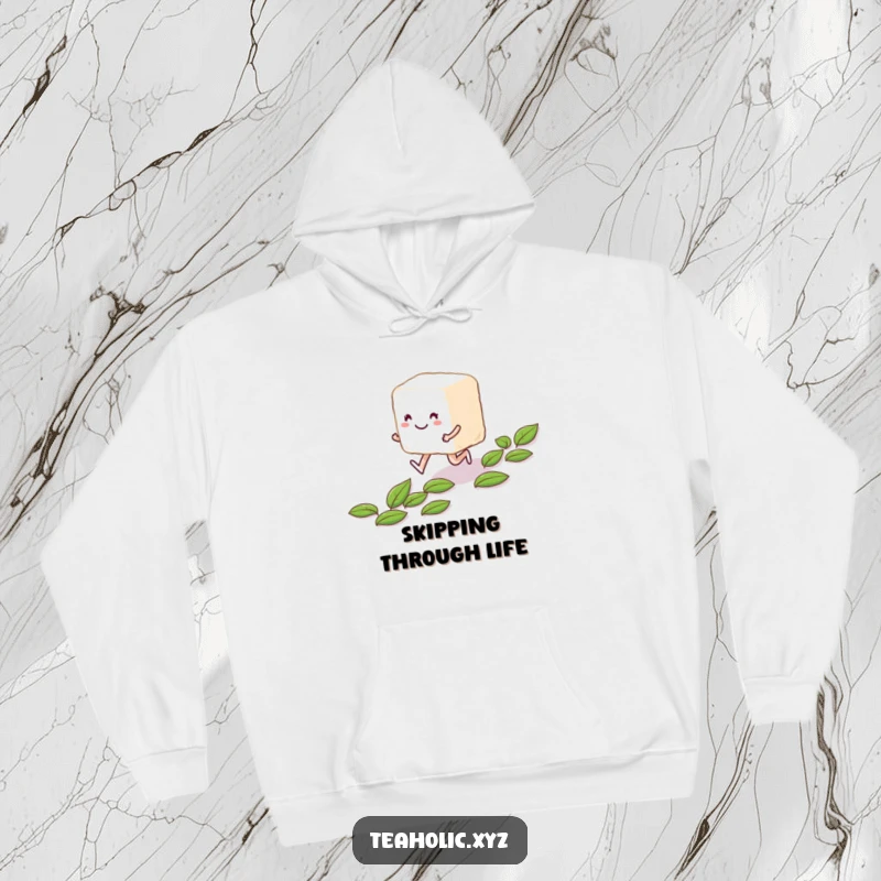 Funny smiling sugar cube character skipping along a path of tea leaves, featured on a cozy hoodie.